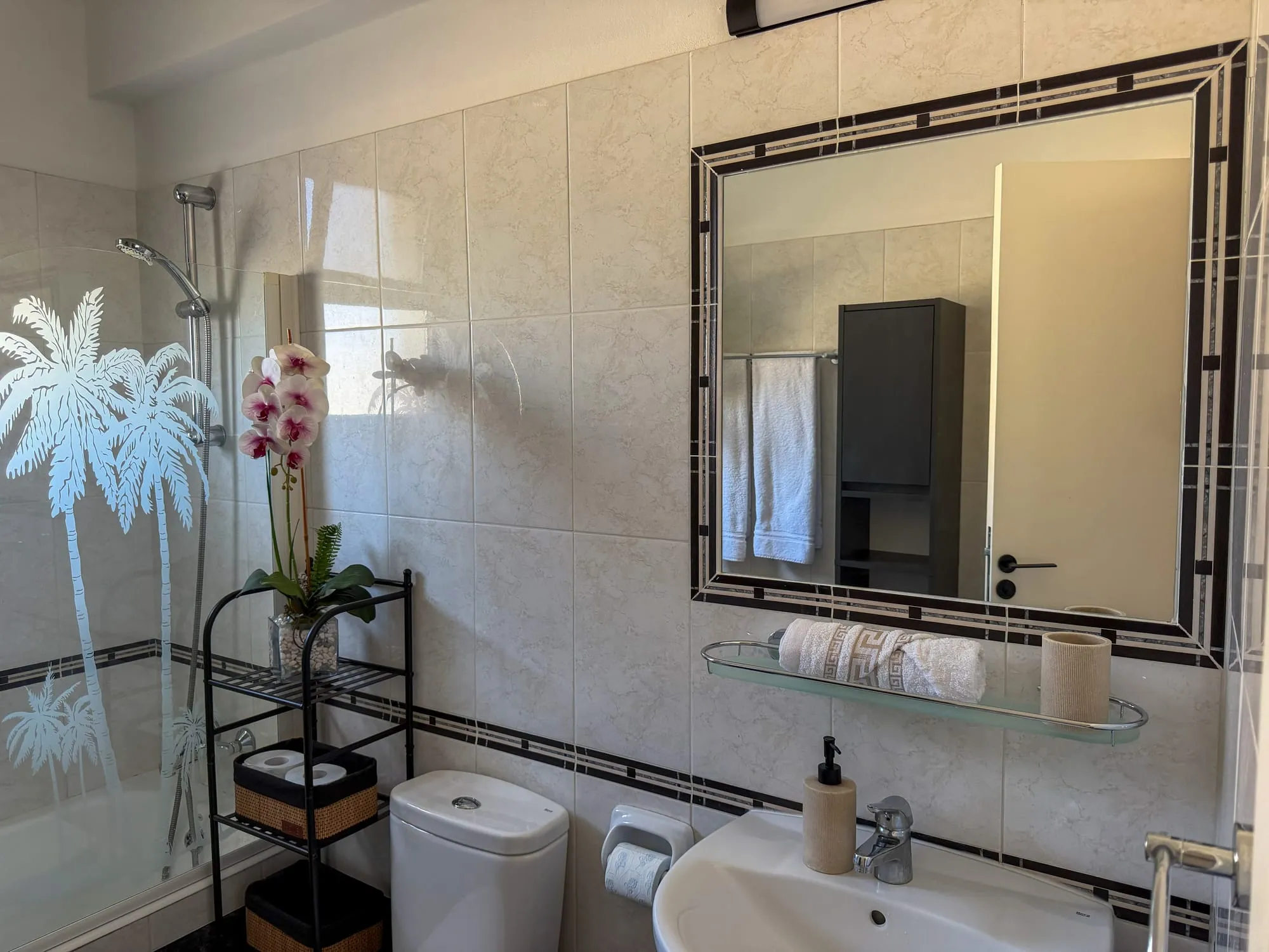 The bathroom, with the palm-etched shower screen, mirror and washbasin