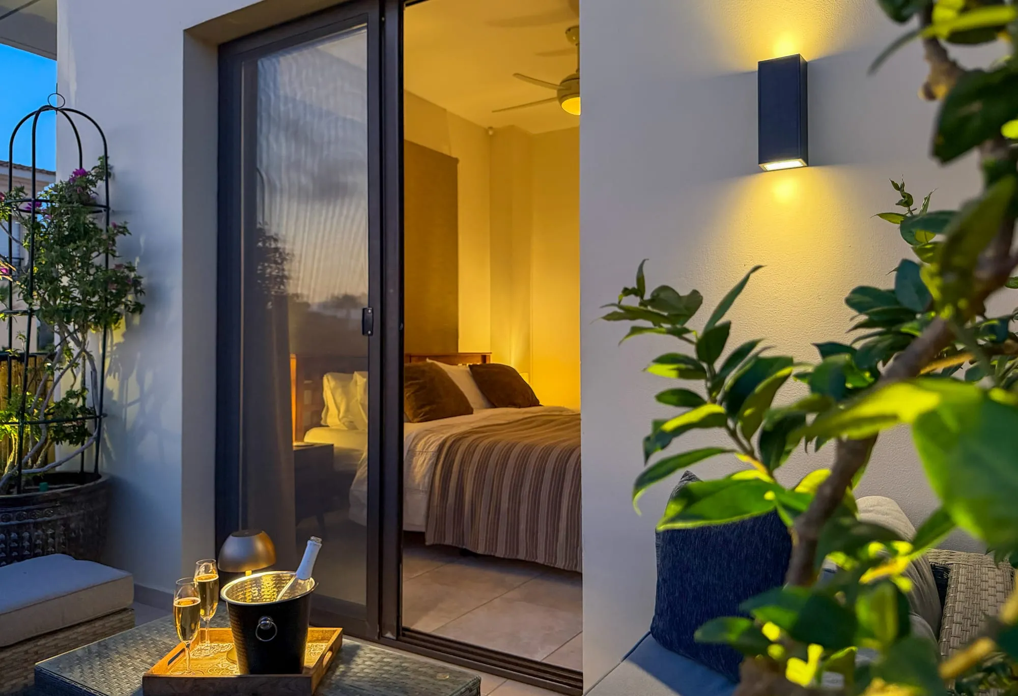 The bedroom at dusk, seen from the rear terrace through the sliding door