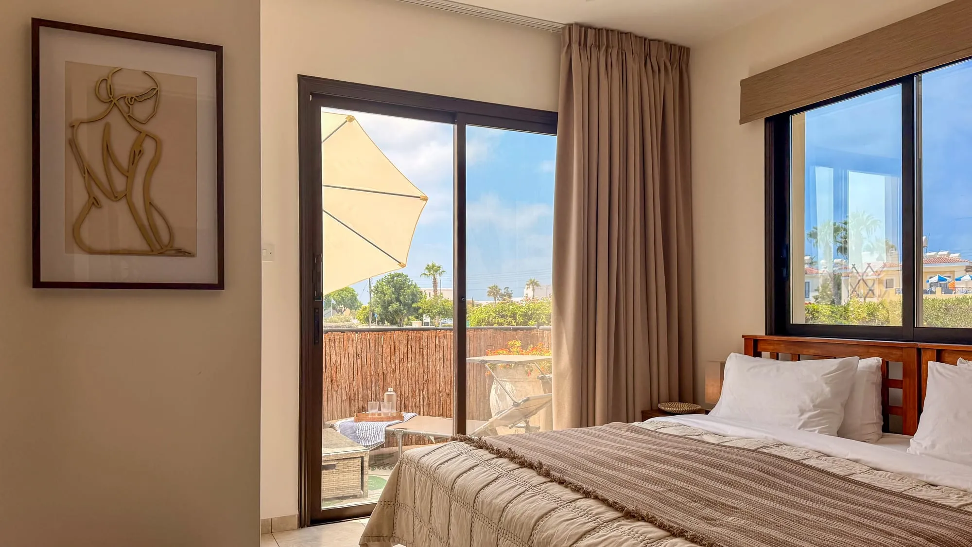 The bedroom, with the balcony and its parasol through the sliding door