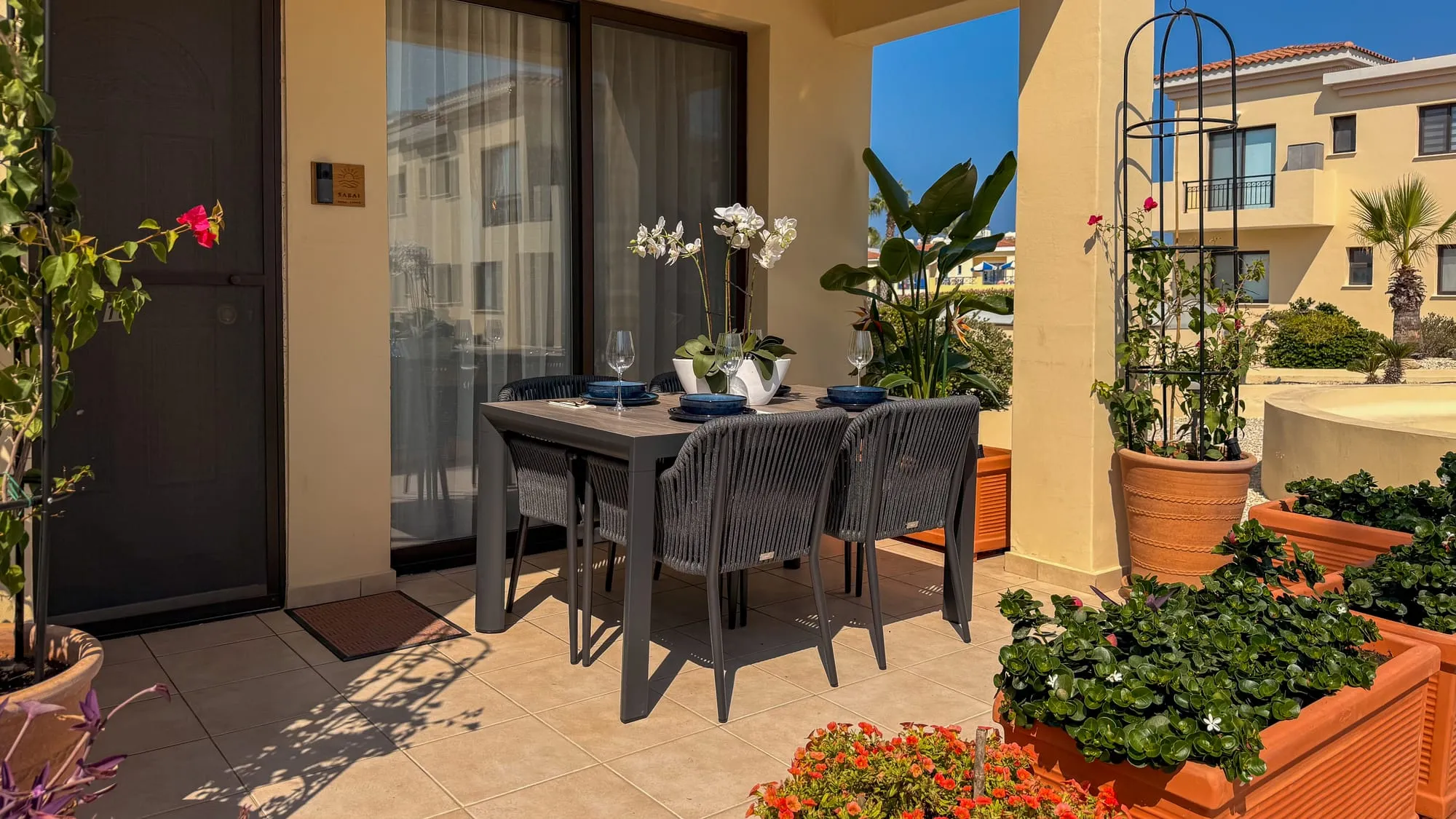 The entrance terrace, with the dining table among potted plants by the front door