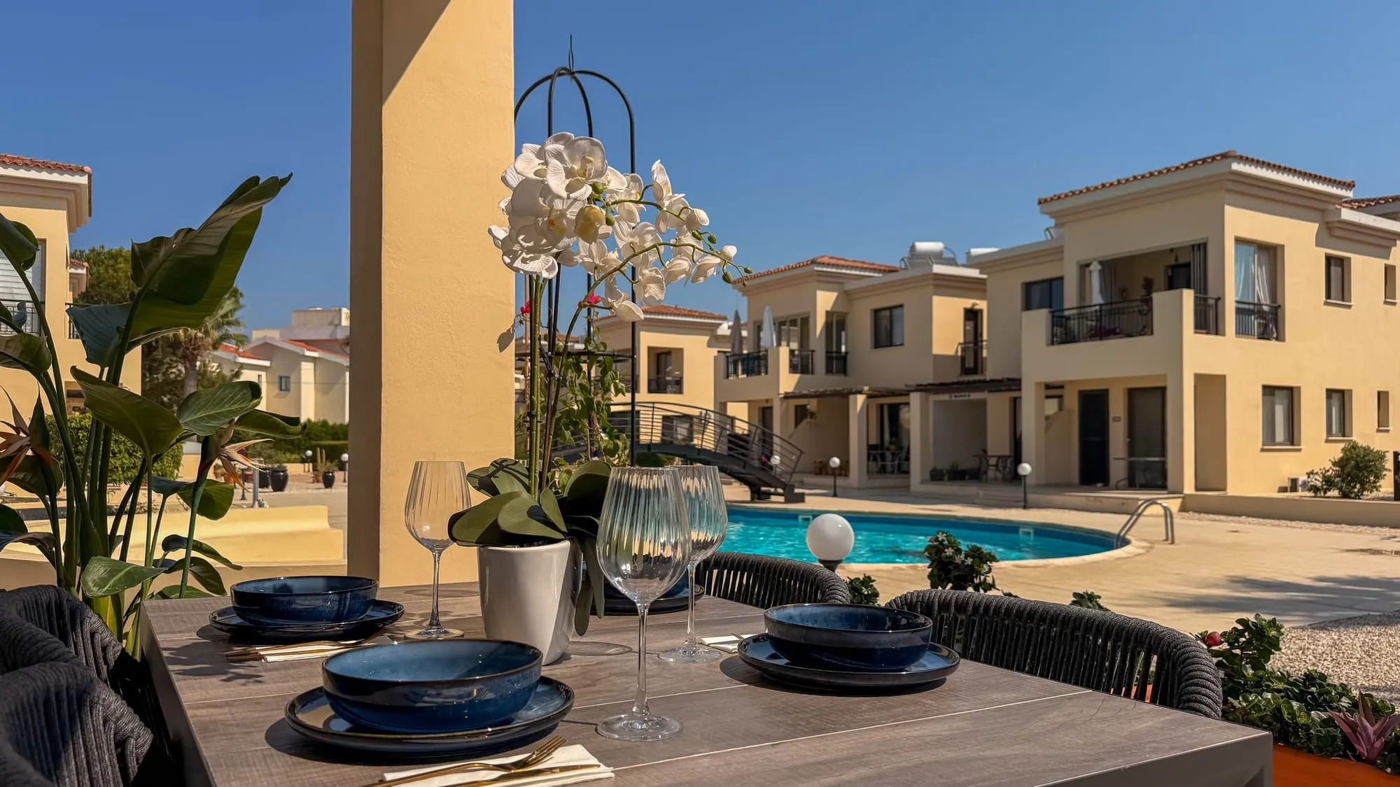 The terrace table set for dinner, looking out over the pool and the garden complex